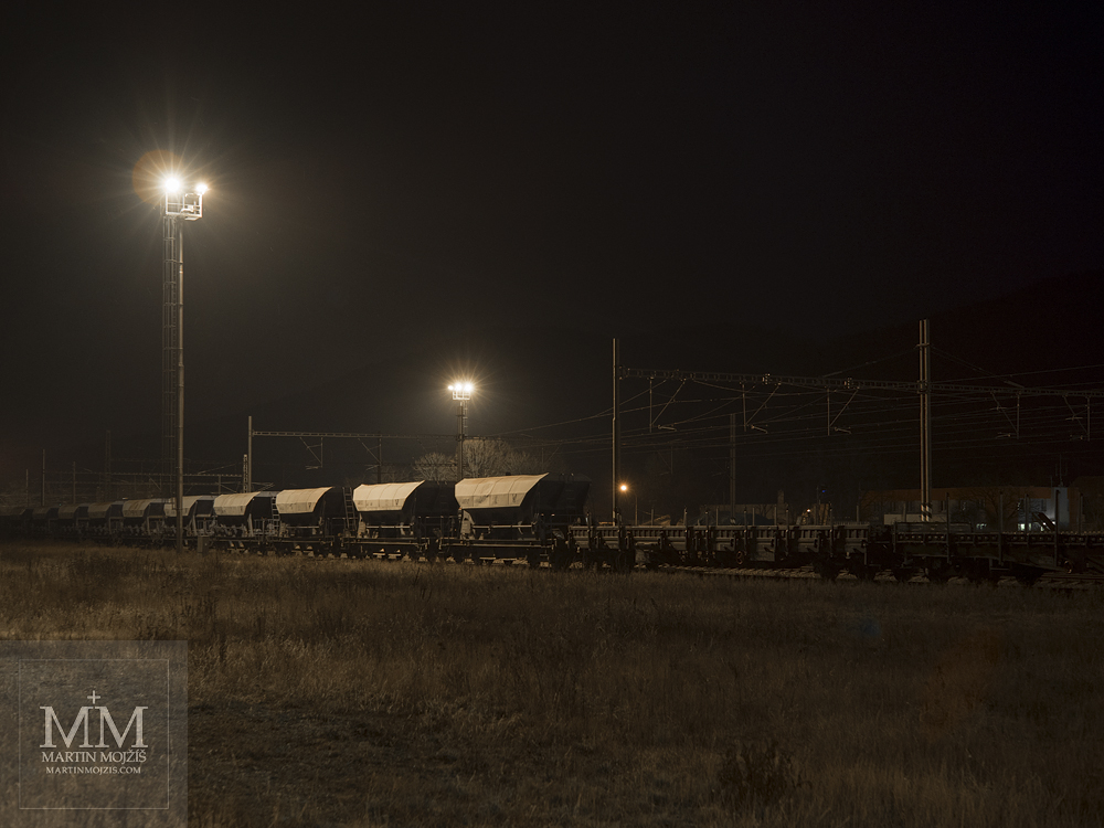 Freight train at a railway station at night. Photograph created with the Olympus M. Zuiko digital ED 25 mm 1:1.2 Pro.