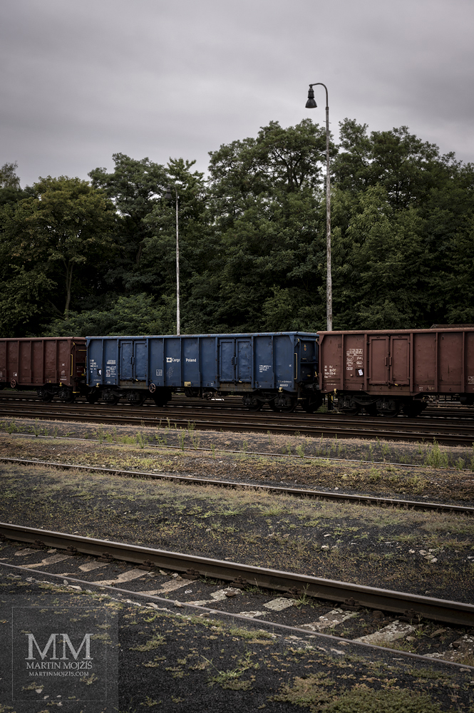 Gravel platforms, freight cars in the background. Railway station Rakovnik.