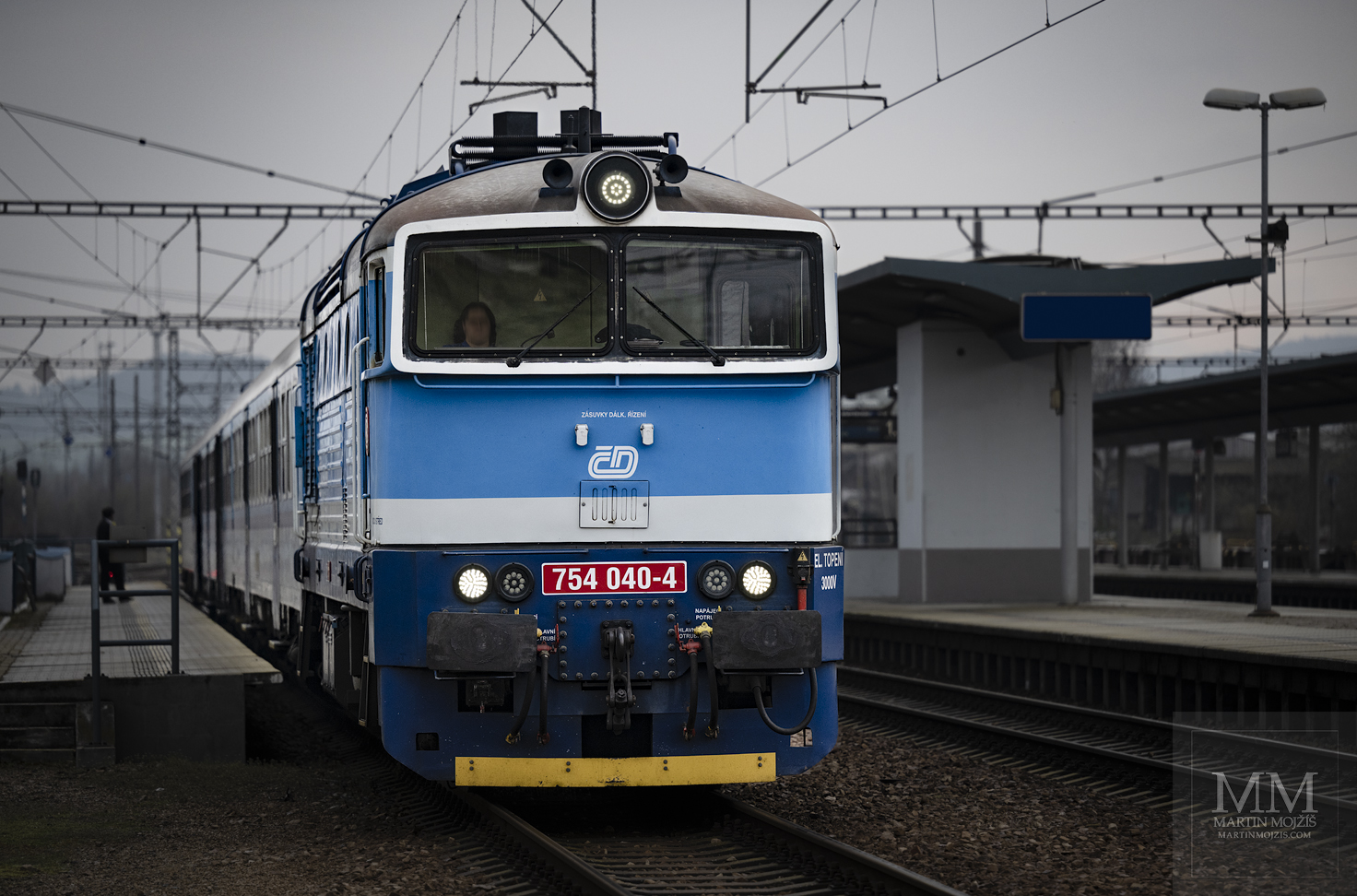 Lokomotiva 754 040-4 v čele osobního vlaku čeká na signál k odjezdu.