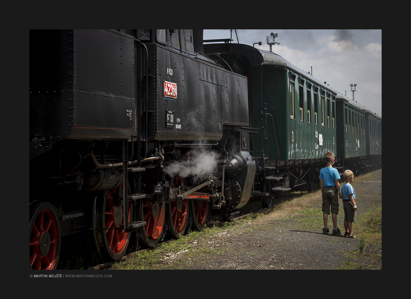 Dva malí kluci stojí u historického parního vlaku. Kolešovka 2017.