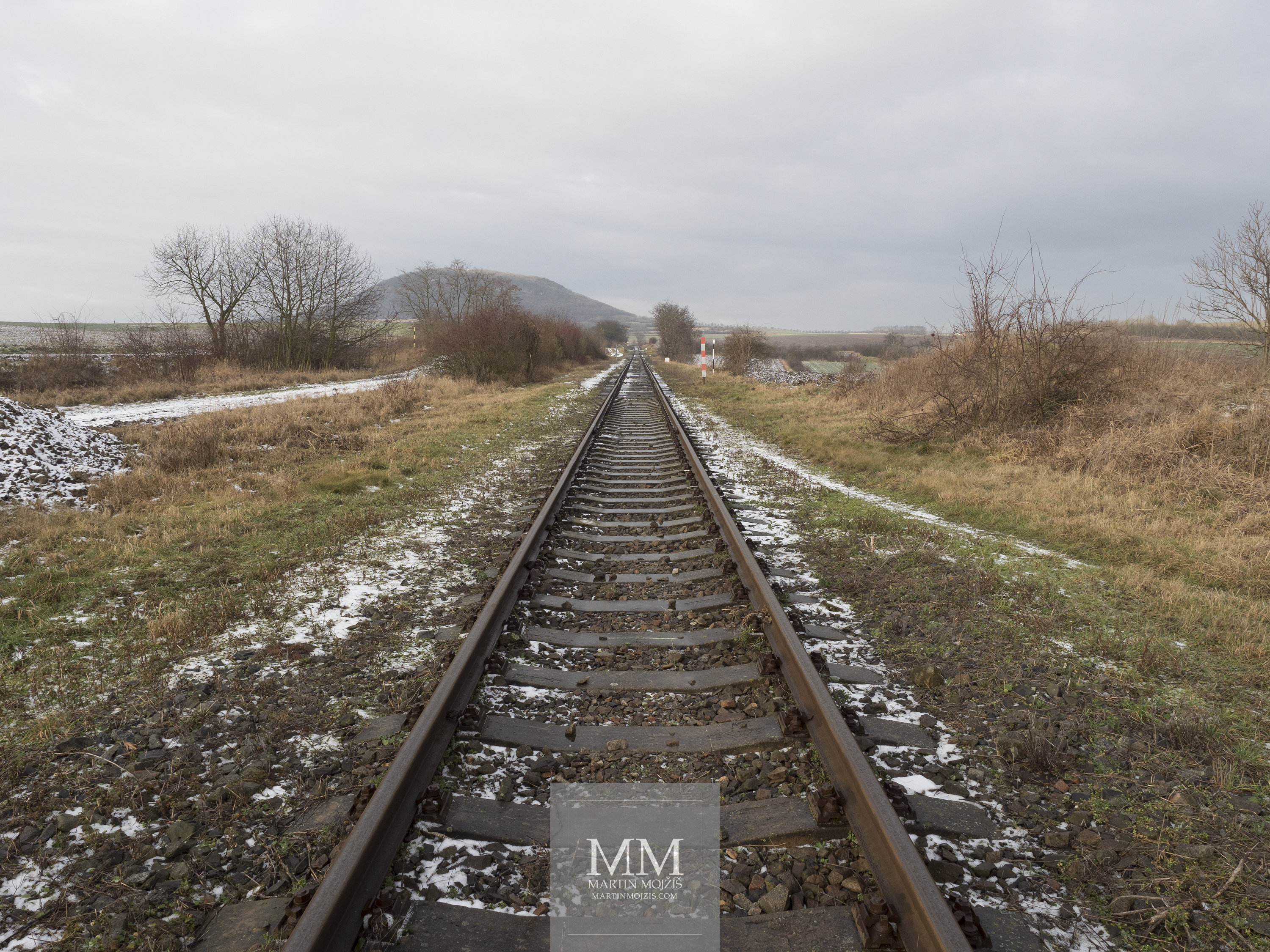 Železniční trať nedaleko hory Říp v zimě. Fotografie vytvořená fotoaparátem Olympus OM-D E-M1 Mark II.