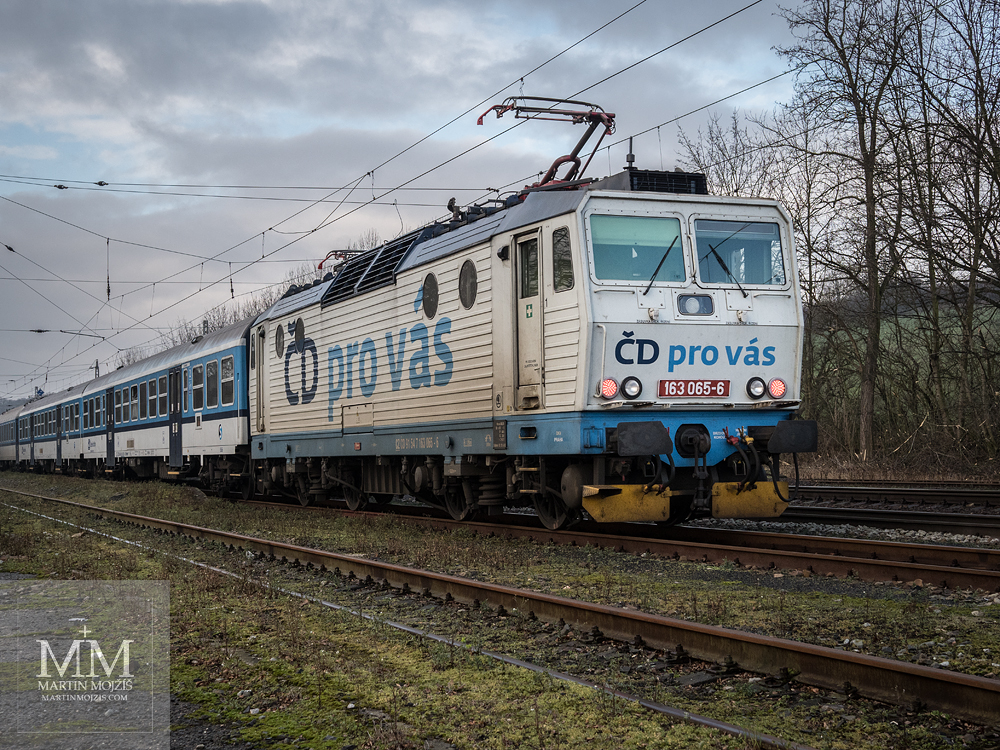 Elektrická lokomotiva 163 065-6 s nápisem ČD pro vás, netradičně zařazena jako postrk osobního vlaku. Fotografie zhotovená objektivem Olympus M. Zuiko digital ED 25 mm 1:1.2 Pro.