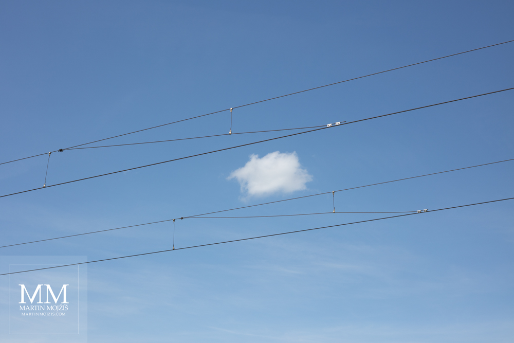 Photograph of a railway catenary line and blue sky with white cloud, created with Canon EF 50 mm 1:1.8 STM lens.