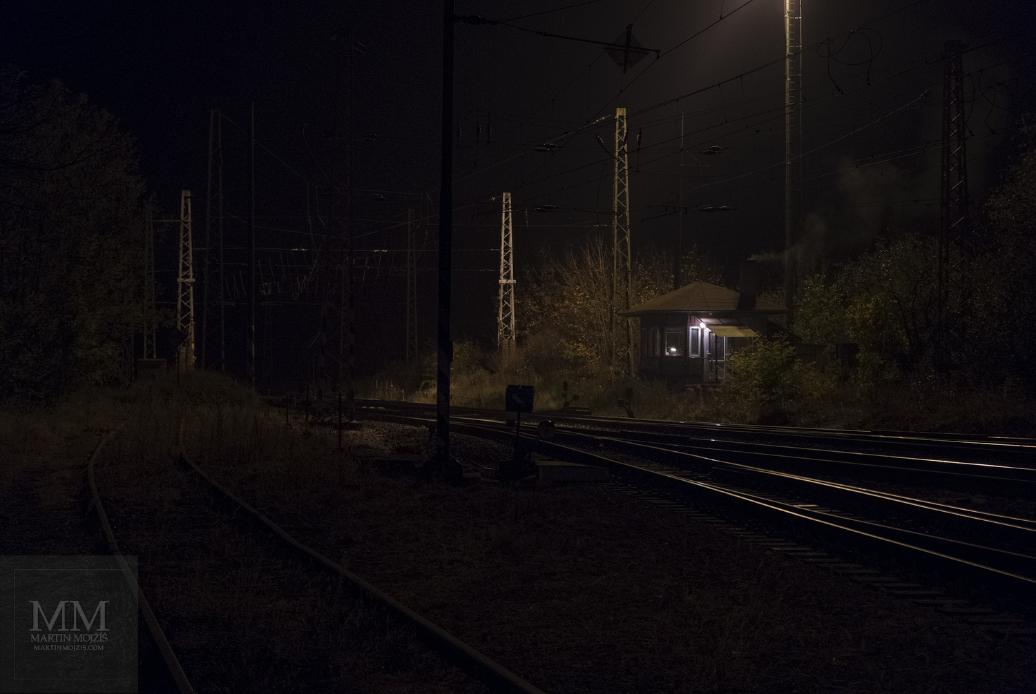 Velkoformátová umělecká fotografie strážního domku u trati v noci. Martin Mojžíš.