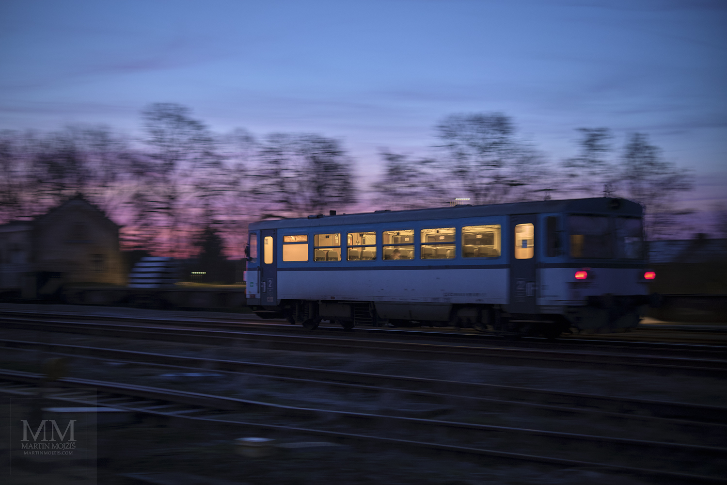 Velkoformátová umělecká fotografie motorového vlaku přijíždějícího na nádraží za soumraku. Martin Mojžíš.