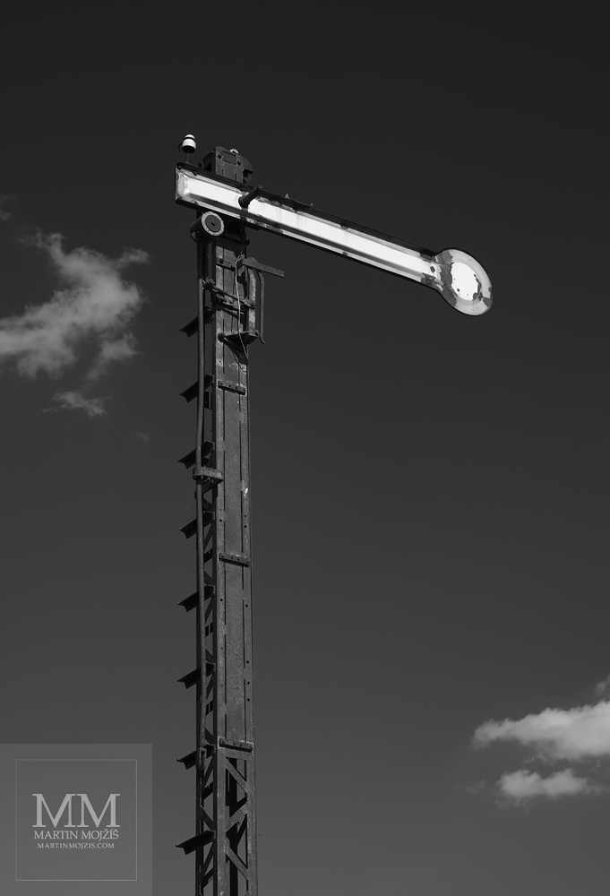 Historické železniční mechanické návěstidlo (semafor) signalizující Stůj, tmavá obloha s bílými mraky. Umělecká černobílá fotografie s názvem ZASTAVENÍ. Fotograf Martin Mojžíš.