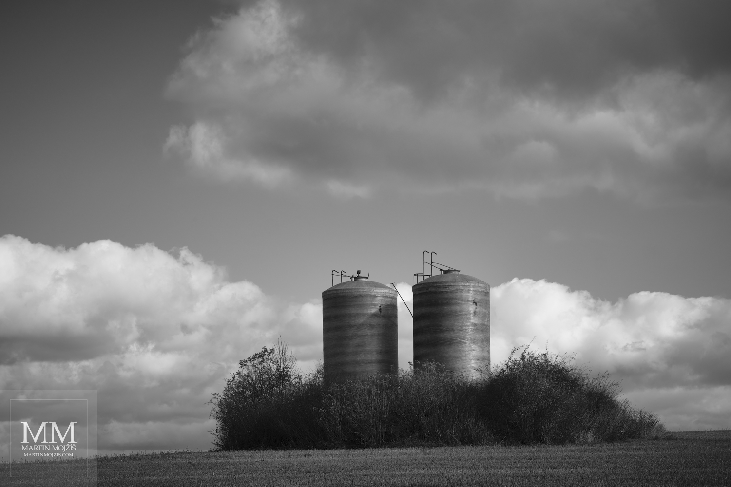 Two vertical cylinders in a field. Black and white fine art photograph A FORGOTTEN SHIP, photographed by Martin Mojzis.