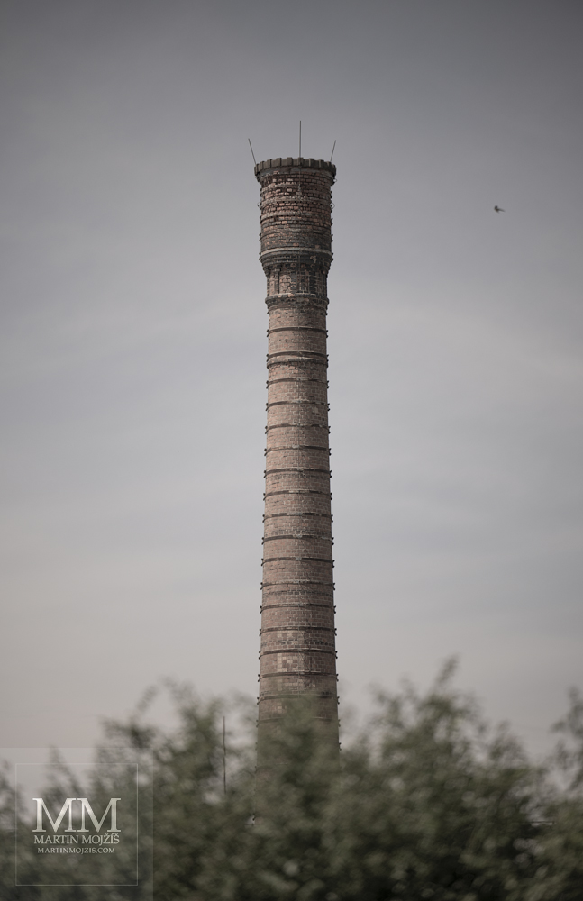 Vysoký cihlový tovární komín. Umělecká fotografie s názvem U TOVÁRNY I. Fotograf Martin Mojžíš.