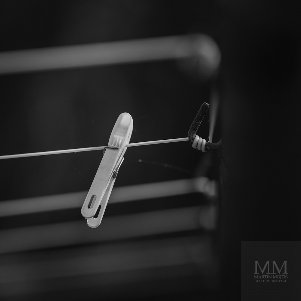 Kolíček na prádlo na šňůře. Umělecká černobílá fotografie s názvem UŽ USCHLO II. Fotograf Martin Mojžíš.