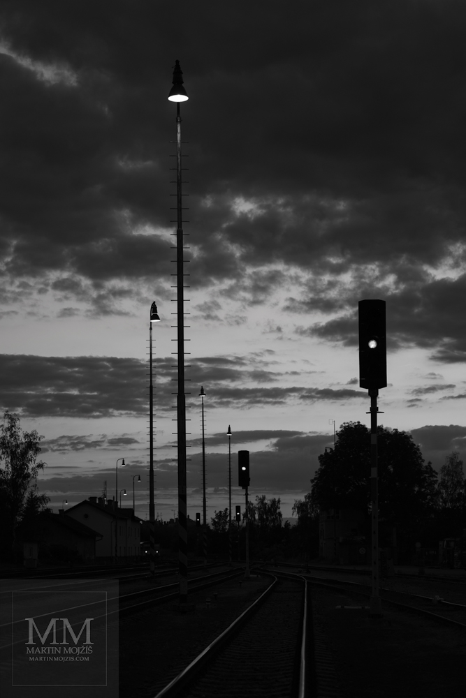 Železniční nádraží v soumraku. Umělecká černobílá fotografie s názvem SOUMRAK NA POČÁTKU LÉTA. Fotograf Martin Mojžíš.