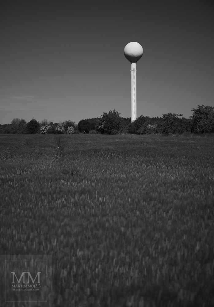 Bílý věžový vodojem v krajině. Umělecká černobílá velkoformátová fotografie s názvem BÍLÝ VODOJEM. Fotograf Martin Mojžíš.