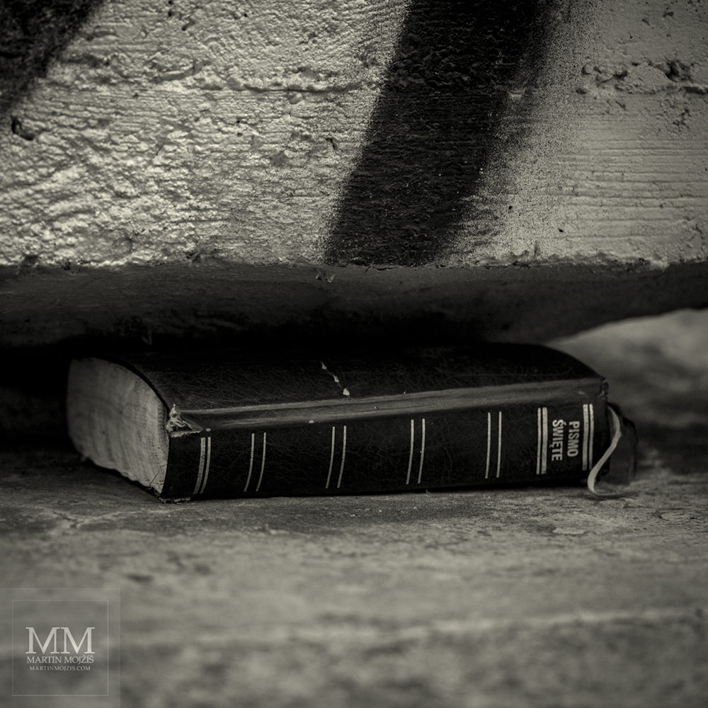 Bible hidden below a bridge pillar. Photograph with title UNDER THE BRIDGE.