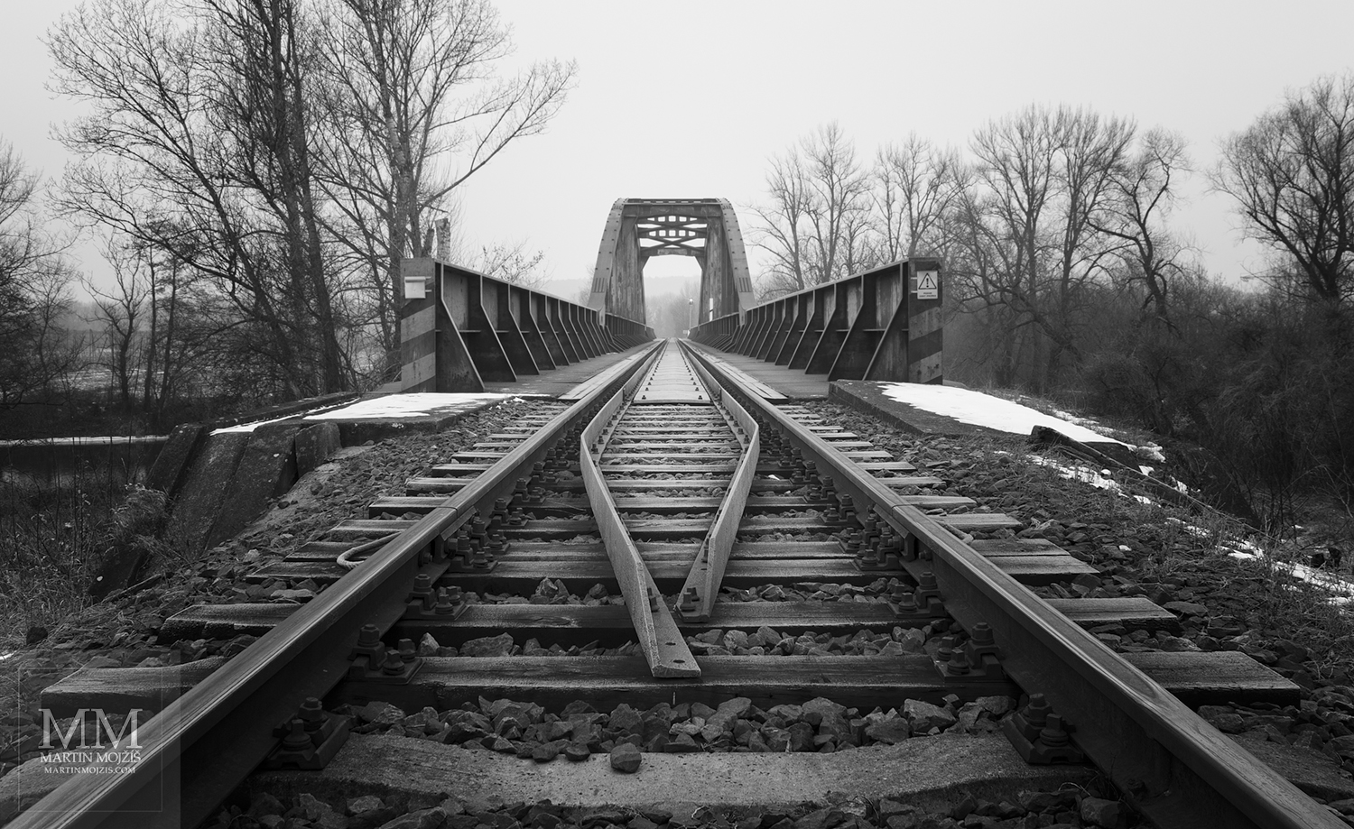 A close up view of the rails in front of the beginning of the bridge. Fine Art black and white photograph of Martin Mojzis with the title IN FRONT OF THE BRIDGE.