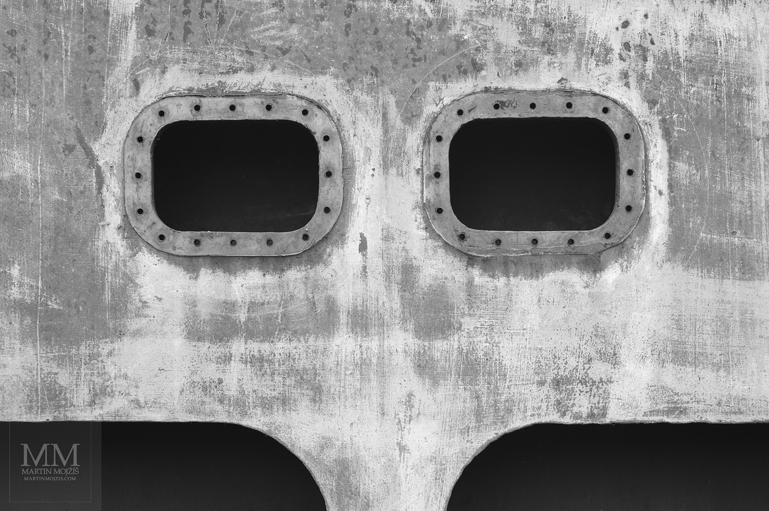 Otvory v ocelovém železničním mostě připomínající obličej. Umělecká černobílá fotografie Martina Mojžíše s názvem CO JSI VIDĚL?