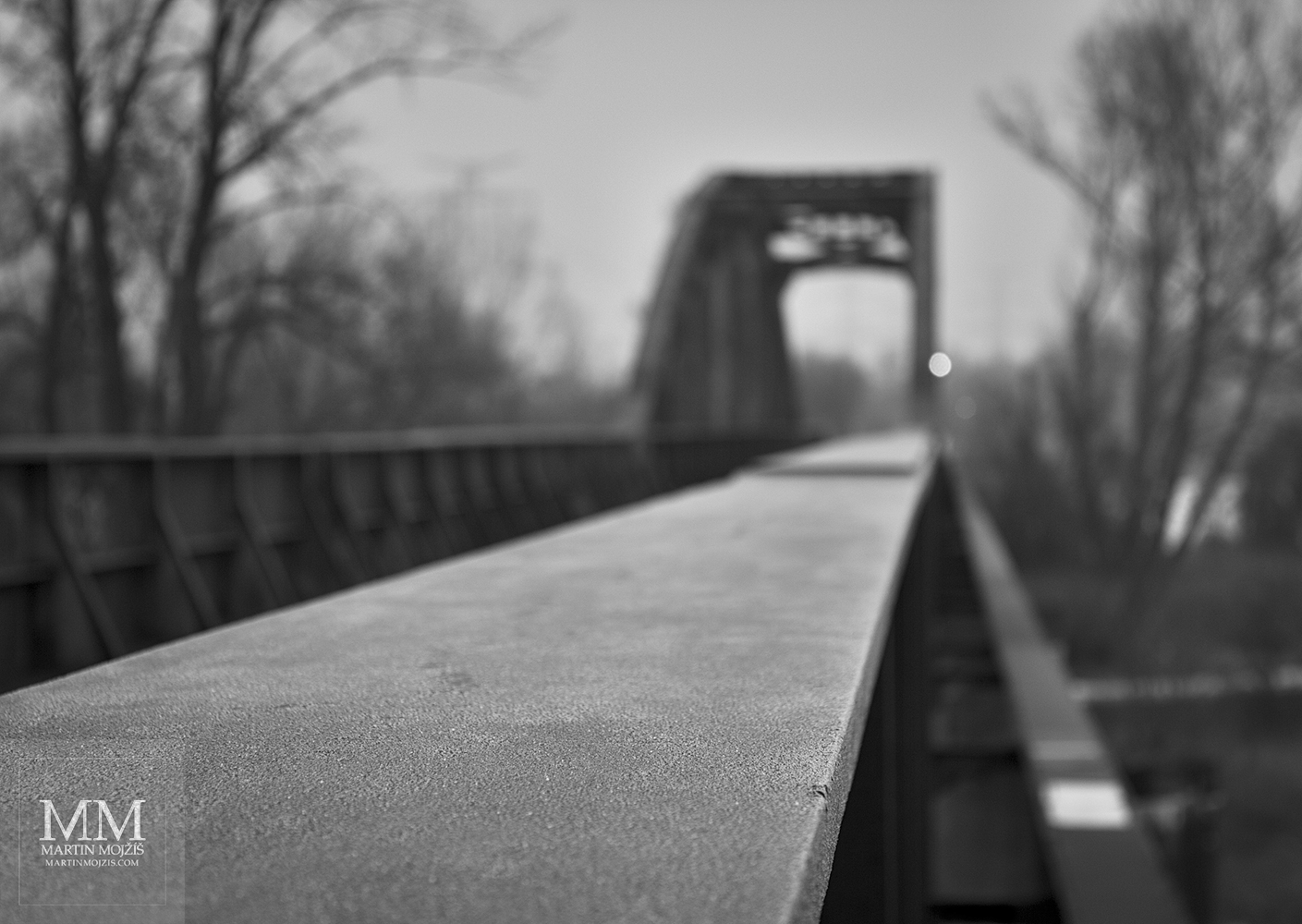 Zábradlí ocelového železničního mostu pokryté jinovatkou. Umělecká černobílá fotografie Martina Mojžíše s názvem ZIMA.