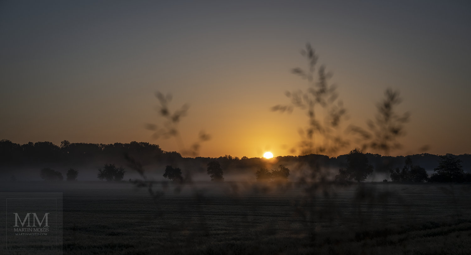 Vycházející Slunce nad obzorem v krajině. Umělecká velkoformátová fotografie V konci května. Fotograf Martin Mojžíš.