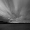 Velkoformátová umělecká fotografie noční krajiny s letícími mraky nad jezerem. Martin Mojžíš.