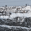 Fotografie velkého, zasněženého lomu u řeky v zimě.