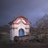 A fallen tree in front of a chapel in a landscape.