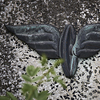 Metal sculpture of a winged railway wheel mounted on a stone.