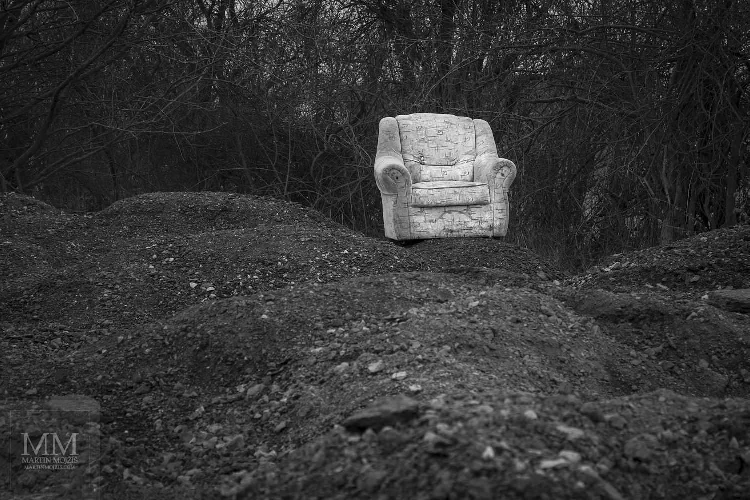An armchair on piles of a gravel. Fine Art black and white photograph by Martin Mojzis with the title WELCOME TO MY HOUSE VI.